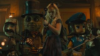 Michelle aims her gun while standing next to some robot mascots in the movie The Electric State