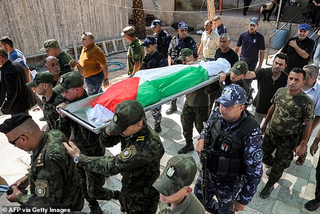 Members of the Palestinian National Security Forces carry the Palestinian flag-draped body of Samer al-Asali, who was killed in Jericho by falling debris from one of the intercepted projectiles fired into Israel by Iran overnight.