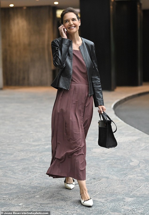 The 45-year-old wore a collarless black leather jacket over a plum-colored pleated dress with cream-colored pointed heels from SARTO by Franco Sarto.