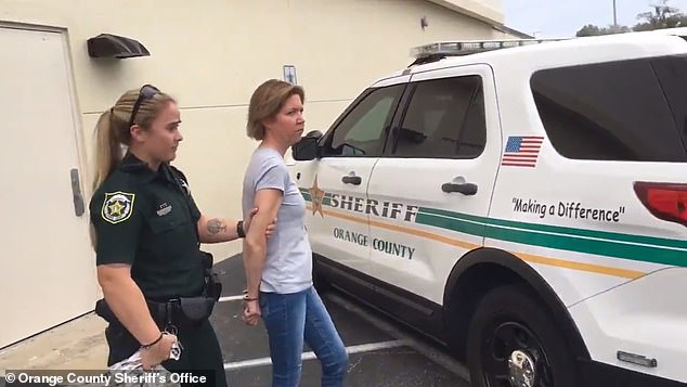 Boone is accompanied by a police officer after her arrest in February 2020. Police discovered videos on her phone that allegedly showed the woman filming Torres begging to be released from the suitcase.