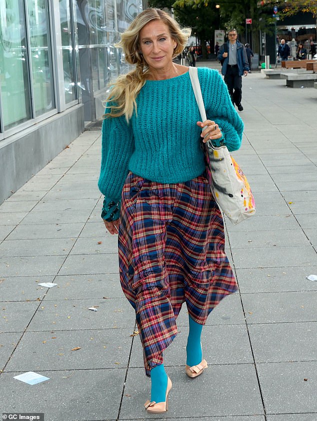 Embracing early fall style, the star wore a turquoise knit sweater and plaid skirt that fell to her ankles