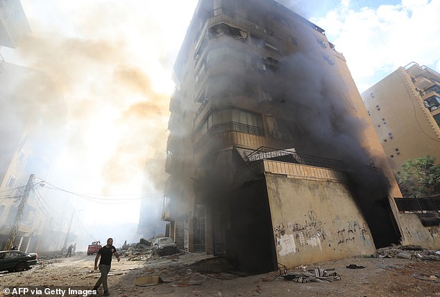 Firefighters work as smoke rises at the site of an overnight Israeli airstrike in Beirut's southern Hadath suburb on October 2, 2024