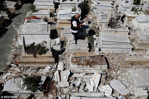 A man inspects the damage at the Bachoura cemetery, which was damaged during an Israeli attack