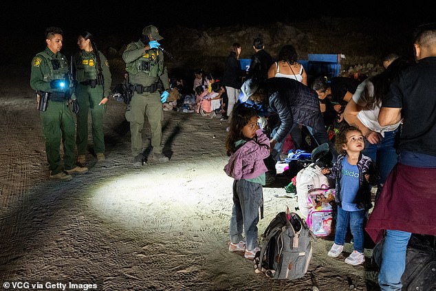 Migrants are met by U.S. Border Patrol agents after crossing into the U.S. from Mexico along an abandoned railroad