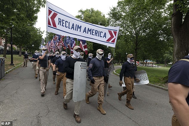 The protesters were all white, dressed identically, and wore white neck gaiters that covered most of their faces. They walked with a banner that said: 'Reclaim America.' on July 2, 2022