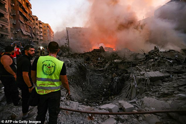 People and rescue workers gather at the rubble of a building destroyed by the Israeli airstrike