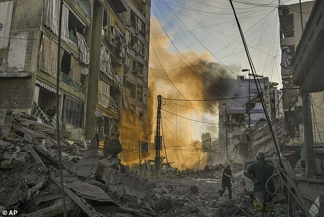 A man takes cover as smoke rises in the background after an Israeli airstrike in Dahiyeh, Beirut, Lebanon, Friday, October 4, 2024