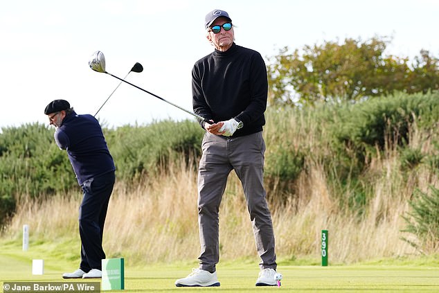 Wearing dark gray chinos, a black turtleneck sweater and a navy blue cap, he looked on after taking his swing, seemingly displeased.