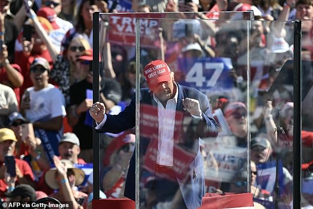 Former U.S. President and Republican presidential candidate Donald Trump dances behind bulletproof glass as he concludes his remarks during a campaign rally at the Aero Center in Wilmington, North Carolina, September 21, 2024