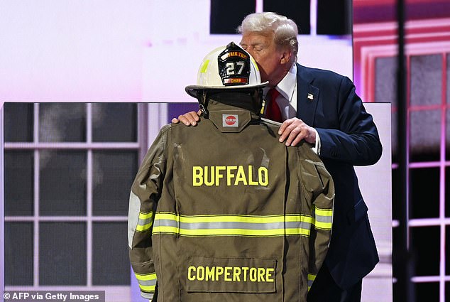 Former US President and 2024 Republican presidential candidate Donald Trump kisses a helmet and fire jacket that belonged to Corey Comperatore