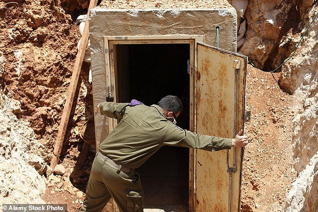 An Israeli army soldier holds open the door to the entrance of a tunnel dug by the Lebanese Islamic political party Hezbollah and militant group