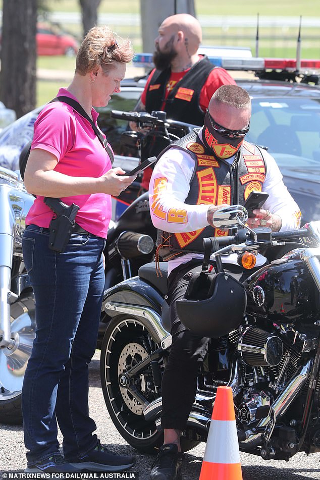 A woman witnesses a man's license being checked as he arrives at the event