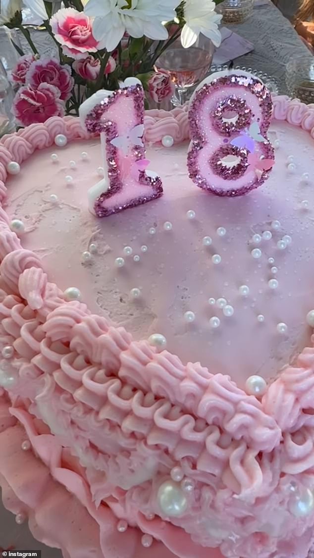 A heart-shaped cake with pink icing, edible pearls and a glittering dark pink '18' candle was placed in front of her