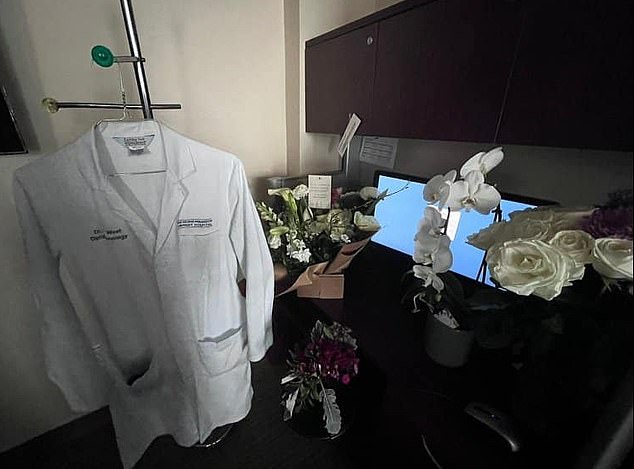 West's empty corner desk is decorated with flower arrangements and his hospital gown