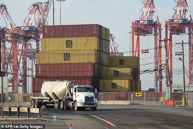 A truck drives past shipping containers in Port Newark, New Jersey. Port workers will return to work after the union and port authorities reached a preliminary agreement on wages and extended the current contract until January 15