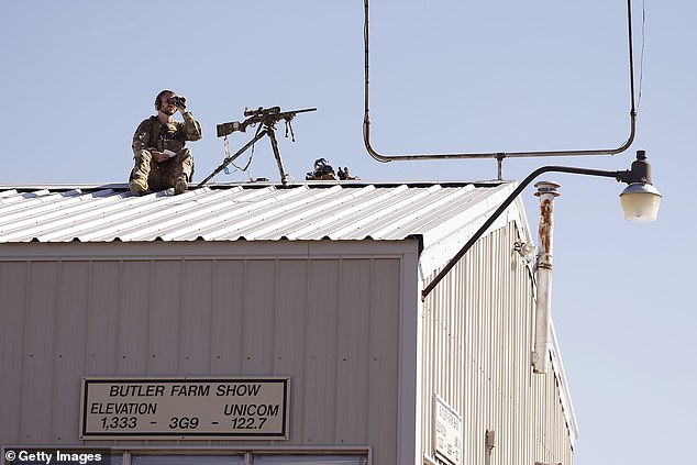 A law enforcement sniper positions himself on a rooftop ahead of a rally by Republican presidential candidate, former US President Donald Trump, at the Butler Farm Show Inc. on October 5, 2024 in Butler, Pennsylvania