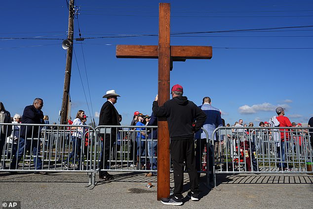 Dan Beasley of Northville, Michigan, holds a cross before Republican presidential candidate, former President Donald Trump, speaks during a campaign rally at the Butler Farm Show