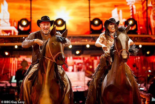 Ex-football player Paul Merson and Karen Hauer pretend to ride horses during their performance