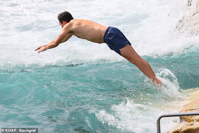 Peter showed off his fit form in navy blue board shorts as he dropped a ball into the waves