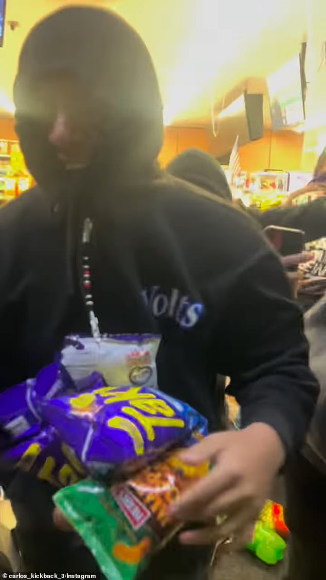 One of the robbers left the store with a smile on his face and his arms filled with bags of chips