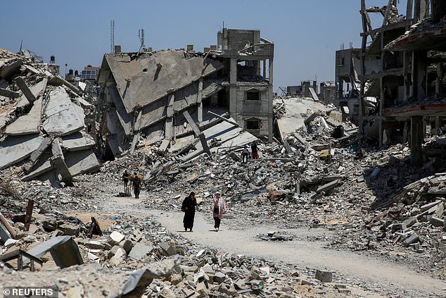 Palestinians walk past the rubble of houses destroyed during the Israeli military offensive, amid the conflict between Israel and Hamas, in Khan Younis in the southern Gaza Strip, July 10, 2024