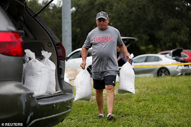 Rene Guerra carries sandbags to be distributed to Pinellas County residents ahead of Tropical Storm Milton's expected arrival in Seminole, Florida on Sunday