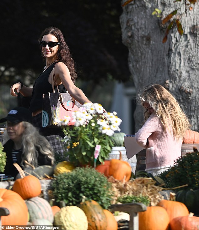 Irina wore sporty, shiny, black sunglasses and carried a Louis Vuitton bag, aptly decorated with painted pumpkins