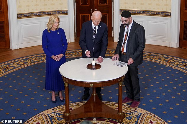 US President Joe Biden, flanked by first lady Jill Biden and Rabbi Aaron Alexander of the Adas Israel Congregation, lights a candle to mark the anniversary of the October 7 Hamas attacks