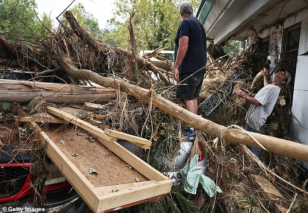 People clean up flood debris from Monteath's Auto Service in the aftermath of Hurricane Helene's flooding along the Swannanoa River on October 4, 2024 in Asheville, North Carolina