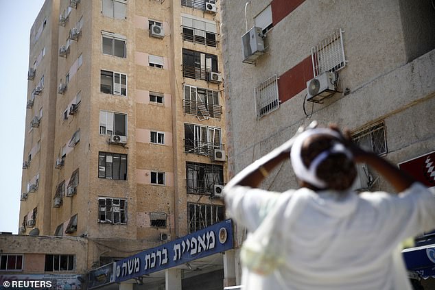 A person reacts to the scene where a rocket fired from Lebanon damaged a residential apartment building as it landed in Israel