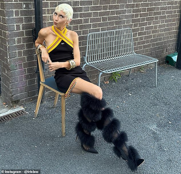 The model stunned in a black halterneck dress with gold detailing as she posed outside