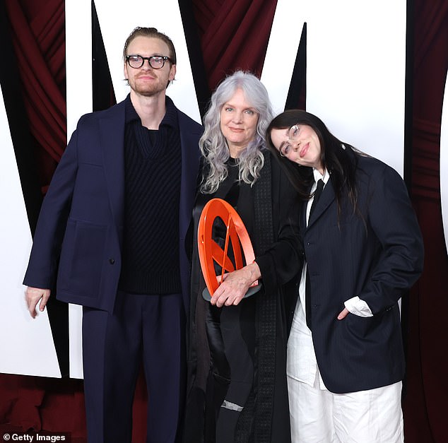 Next to her, Billie wore an oversized pinstripe blazer, which she wore over a white button-down and a black satin tie. Finneas also dressed to impress, opting for a monochrome, navy blue outfit