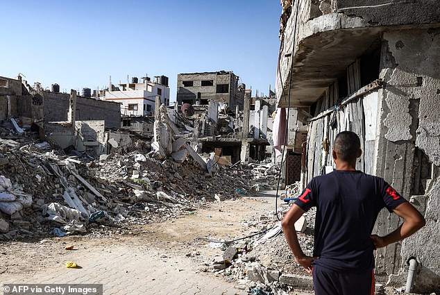 A man stands in front of a collapsed building in the Bureij camp for Palestinian refugees in the central Gaza Strip on October 9