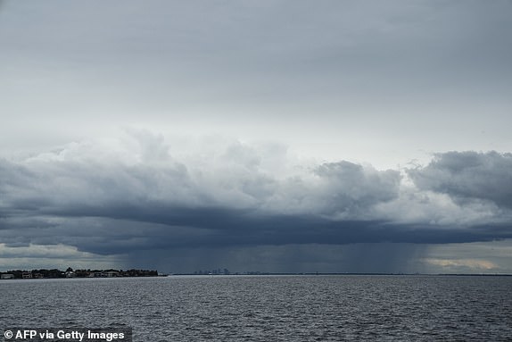 TOPSHOT - In the distance of St. Petersburg, Florida, a thunderstorm can be seen moving over Tampa ahead of Hurricane Milton's expected landfall mid-week on October 8, 2024. Storm-ravaged Florida encircles Tuesday for a direct hit from hurricane Milton, a monstrous weather system that threatens catastrophic damage and forces President Joe Biden to postpone a major overseas trip. (Photo by Bryan R. SMITH/AFP) (Photo by BRYAN R. SMITH/AFP via Getty Images)