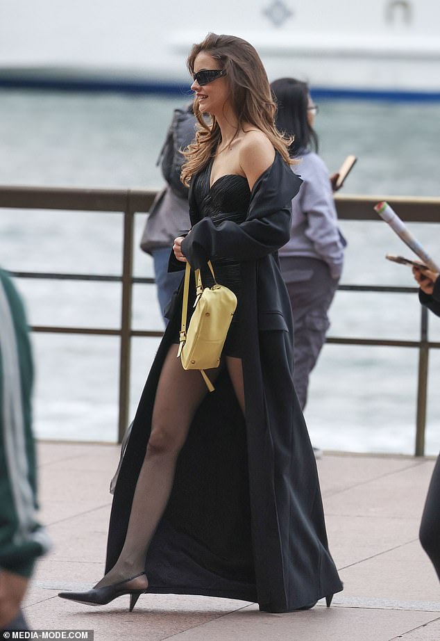 She also wore a glamorous long black coat and accessorized with a yellow Versace handbag worth $2,200