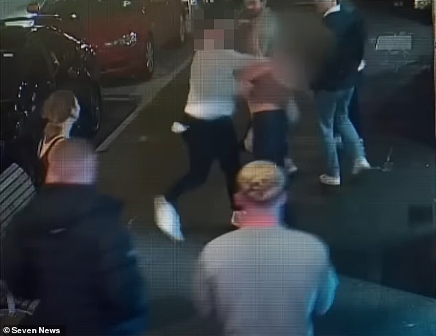 The Brisbane Lions fan (pictured center) pulls his arm back before slamming his fist into Poppy's jaw, sending the young tourist flying backwards into a wall