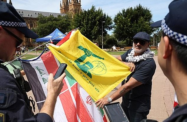 Images have since emerged of Yazbek also holding a green and gold flag in the colors of Hezbollah with a Ned Kelly-like figure (pictured)