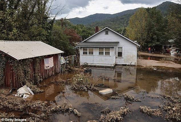 An American flag hangs over the water left after Hurricane Helene in Swannanoa, North Carolina