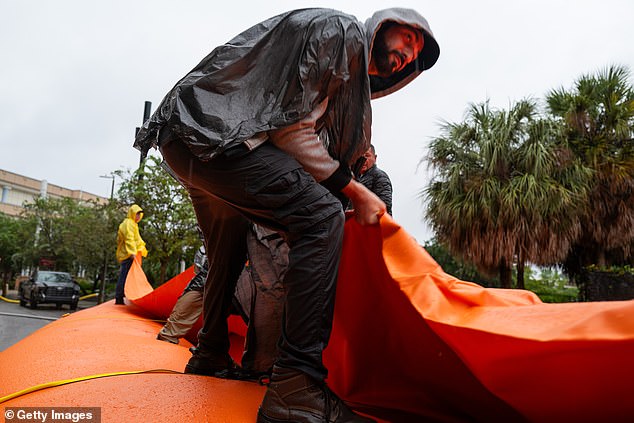 As Tampa prepares for the arrival of Hurricane Milton, workers help the National Guard build a flood barrier around a city wastewater facility