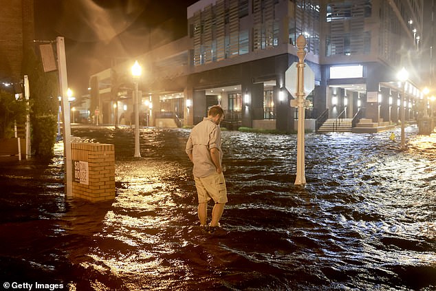 A man walks through the water flooding the street after Hurricane Milton made landfall in the Sarasota area on Wednesday