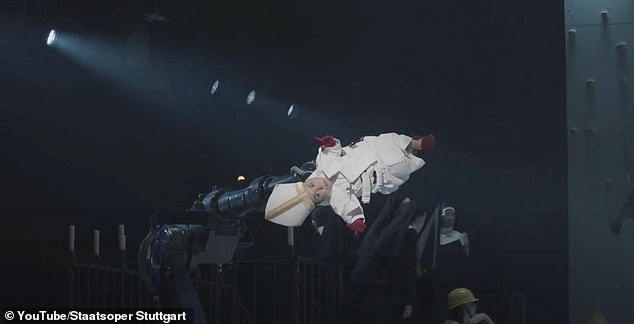 At one point, an actress with dwarfism is dressed up as the Pope is lifted into the air and spun by a robotic arm