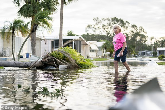 OSPREY, FLORIDA - OCTOBER 10: A woman walks along a flooded street in the aftermath of Hurricane Milton on October 10, 2024 in Osprey, Florida. The hurricane made landfall as a Category 3 hurricane in the Siesta Key area. (Photo by Sean Rayford/Getty Images)