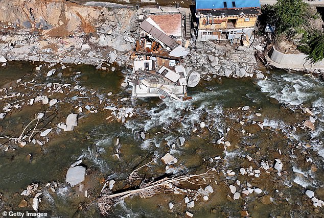 An aerial view of people standing near destroyed and damaged buildings in the aftermath of Hurricane Helene's flooding on October 8, 2024 in Bat Cave, North Carolina