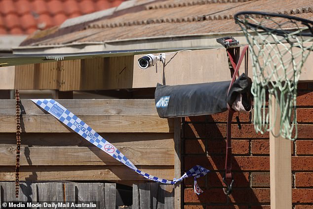 Police tape can be seen on the back fence of the building