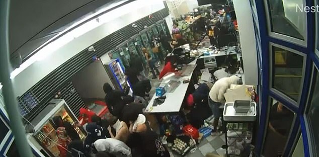 A huge crowd robs the Oakland gas station after a car crashes into the glass to break in