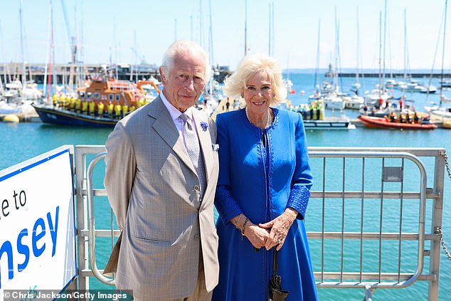 King Charles III and Queen Camilla pose in front of the RNLI lifeboats during an official visit to Guernsey on July 16