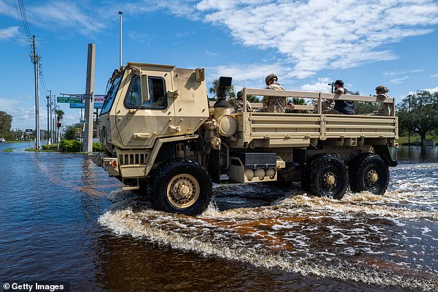 A National Guard truck drove through water on a road on October 11 after the Anclote River flooded homes, businesses and roads during Hurricane Milton's passage over Florida