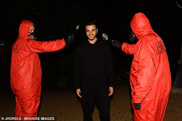 In a subsequent photo, Junior beamed as he posed for the camera next to two men in red hazmat suits and face coverings