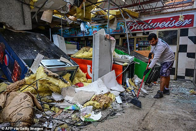 A man clears debris at a gas station store in Lakewood Park, Florida, in the aftermath of Hurricane Milton