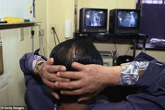 This practice involves cutting off people's fingers as an apologetic gesture for a serious mistake. It is currently unclear why the gangster cut off his finger (file image of a yakuza member looking at security monitors)